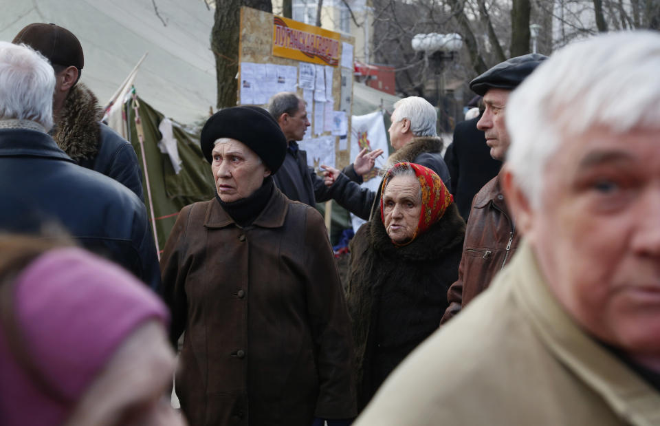 In this photo taken Tuesday, March 11, 2014, men debate as people gather in a pro Russian camp in Luhansk, eastern Ukraine. The breakup of the Soviet Union and harsh economic realities of the market haven’t been kind to many local employers. Residents say many factories, including the locomotive works, have had to drastically cut both payrolls and production. Since Russian troops rolled into Crimea, and lawmakers there scheduled a referendum for Sunday on whether to join Russia, the world’s attention has focused on the fate of the lush peninsula that juts into the Black Sea. But here in Ukraine’s coal-fired industrial east, where Russians have lived for more than two centuries, a potent mix of economic depression, ethnic solidarity and nostalgia for the certainties of the Soviet past have many demanding the right to become part of Russia as well (AP Photo/Sergei Grits)