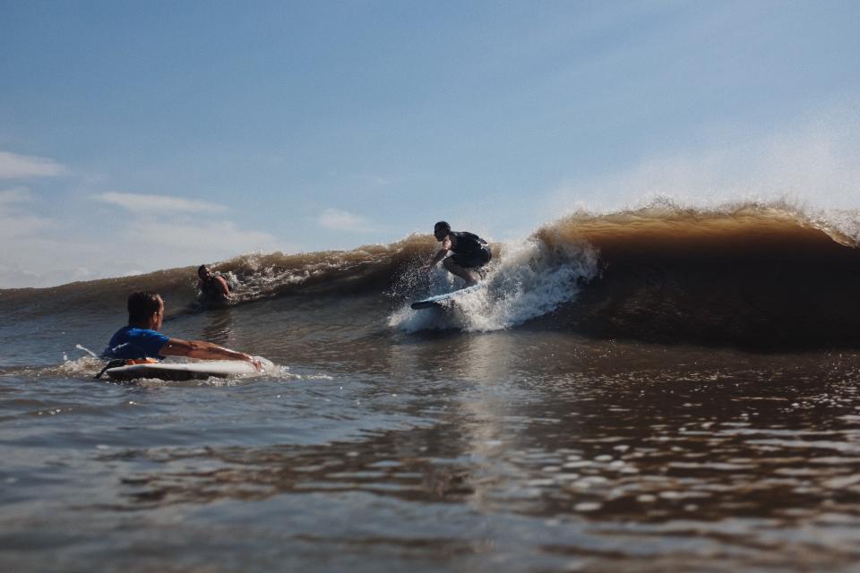 A surfer catches a wave off Grand Isle in the silty, rich water of the Gulf of Mexico