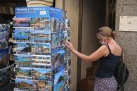 A woman shops for postcards in town of Sóller in the Balearic Island of Mallorca, Spain, Monday, July 27, 2020. Britain has put Spain back on its unsafe list and announced Saturday that travelers arriving in the U.K. from Spain must now quarantine for 14 days. (AP Photo/Joan Mateu)