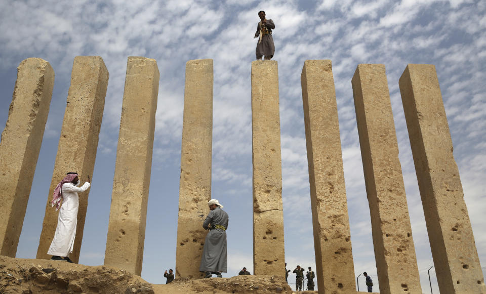 FILE - In this Feb. 3, 2018 file photo, a Yemeni militiaman stands atop a limestone column at the Awwam Temple, also known as the Mahram Bilqis, in Marib, Yemen. A prominent Yemeni rights group has documented heavy damage to at least 34 archaeological sites from the fighting and airstrikes over the past four years. In a report released Thursday, Nov. 15, 2018, the Mawatana Organization for Human Rights said that it collected testimonies from over 75 people working at the archaeological sites and monuments that came under attack since mid-2014. (AP Photo/Jon Gambrell, File)