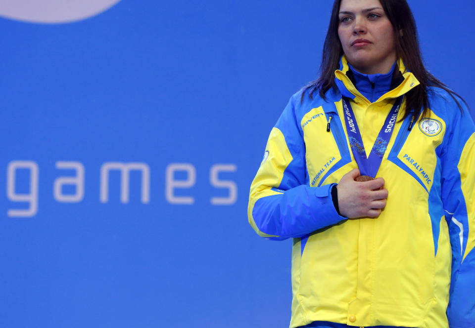 Ukraine's Olena Iurkovska covers her bronze medal with her hand after finishing third in the women's biathlon 12,5 km sitting during a medal ceremony at the 2014 Winter Paralympics, Friday, March 14, 2014, in Krasnaya Polyana, Russia. The majority of Ukraine's Paralympic medalists covered their medals during medal ceremonies. (AP Photo/Dmitry Lovetsky)