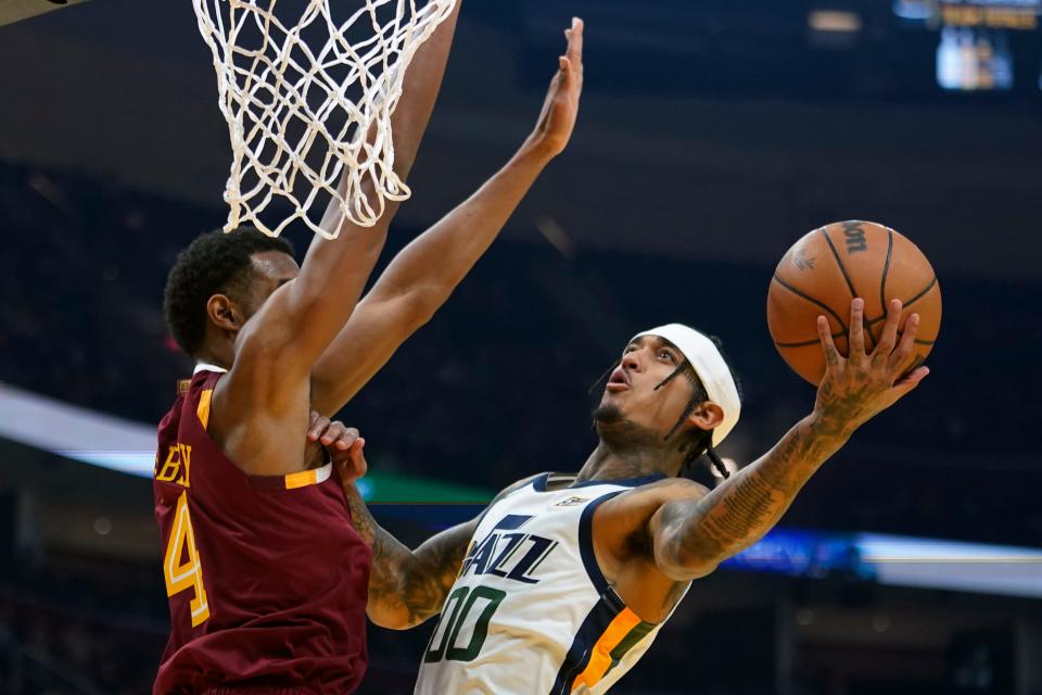 Utah Jazz's Jordan Clarkson (00) drives to the basket again Cleveland Cavaliers' Evan Mobley (4) in the first half of an NBA basketball game, Sunday, Dec. 5, 2021, in Cleveland. (AP Photo/Tony Dejak)