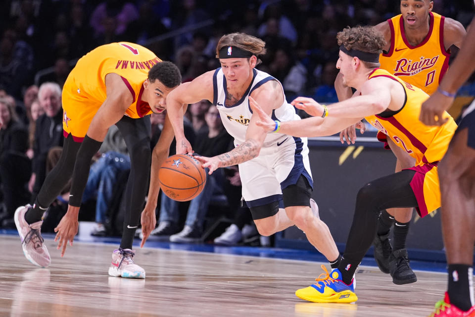 Mac McClung, second from left, of the Osceola Magic, picks up the ball between Victor Wembanyama, left, of the San Antonio Spurs, and Brandin Podziemski, front right, of the Golden State Warriors, during an NBA Rising Stars basketball game in Indianapolis, Friday, Feb. 16, 2024. (AP Photo/Michael Conroy)