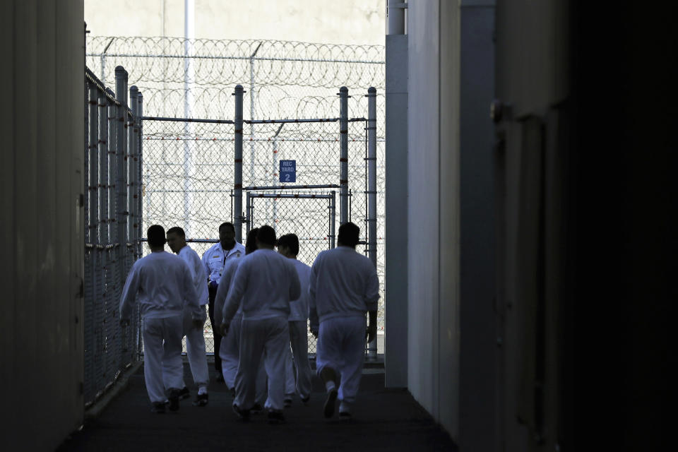 In this photo taken Sept. 10, 2019, detainees walk toward a fenced recreation area at the GEO Group’s immigration jail in Tacoma, Wash., during a media tour. After nearly four years of litigation and pandemic-related delays, a federal jury on Tuesday, June 15, 2021, began deliberating whether the GEO Group must pay minimum wage to detainees who perform cooking, cleaning and other tasks at the facility – instead of the $1 per day they typically receive. (AP Photo/Ted S. Warren)