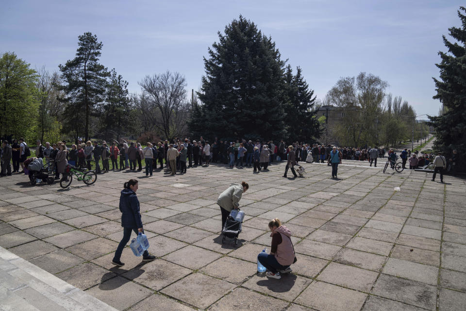 Local residents stand in line to receive drinking water at a distribution centre in Toretsk, eastern Ukraine, Monday, April 25, 2022. Toretsk residents have had no access to water for more than two months because of the war. (AP Photo/Evgeniy Maloletka)