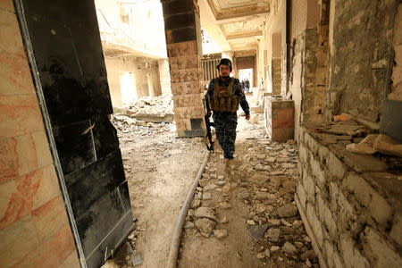 A federal policeman walks at a destroyed train station during a battle against Islamic State militants, in Mosul, Iraq March 19, 2017. REUTERS/Thaier Al-Sudani