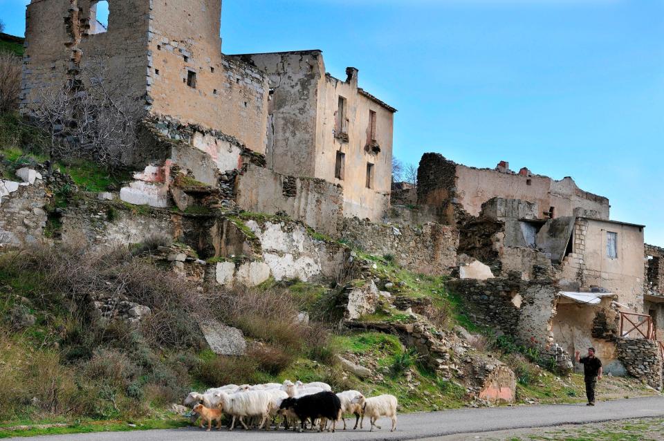 A man walking his sheep in an abandoned town of Sardinia.