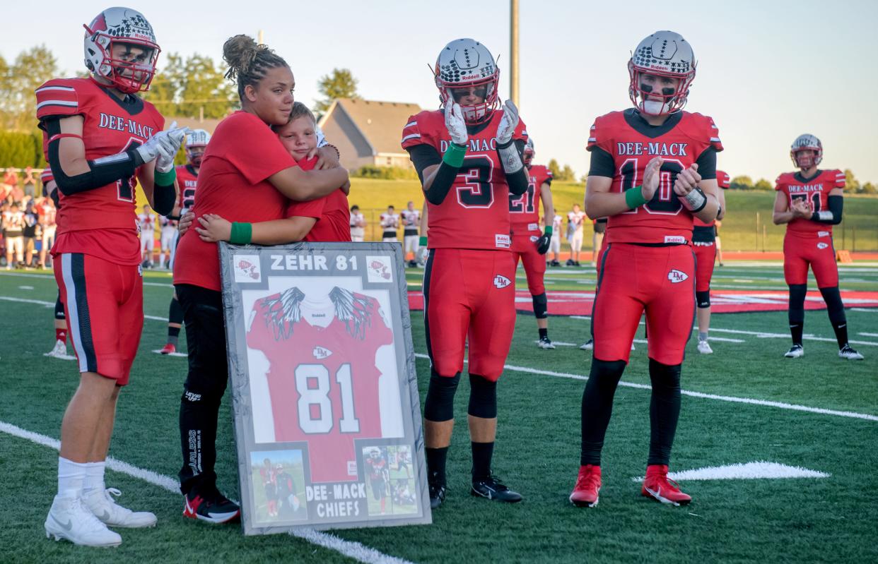 Lydia Zehr of Mackinaw hugs her son Carter during a ceremony honoring her other son Adrian, 9, who was killed in a car accident in July, before the start of a football game Friday, Sept. 1, 2023 between Dee-Mack and Gibson City-Melvin-Sibley in Mackinaw.