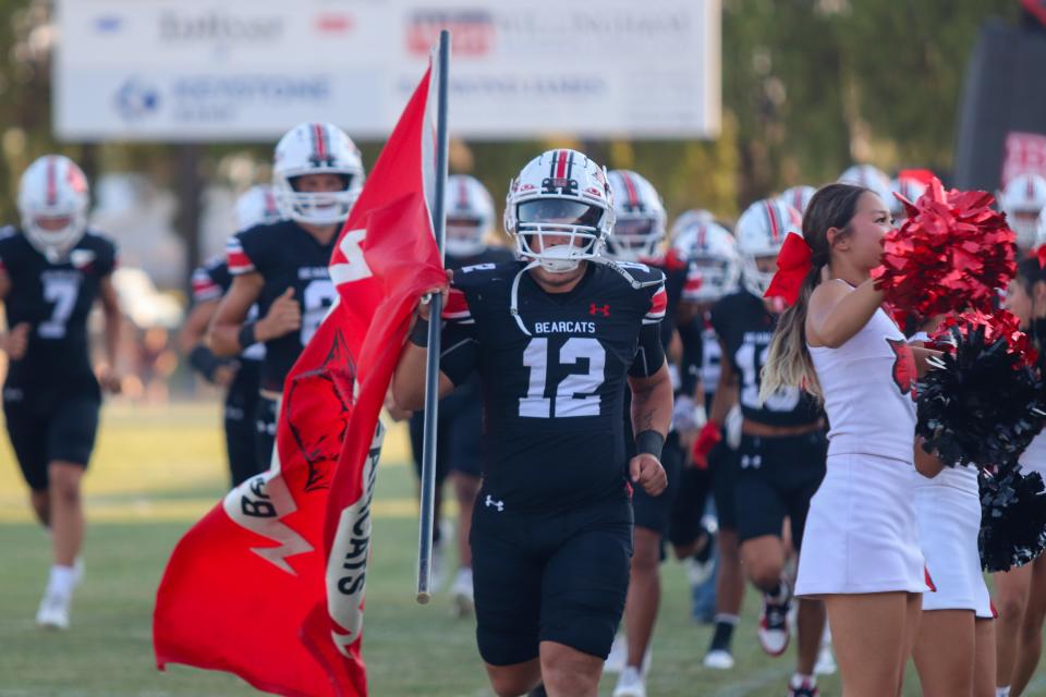 Ballinger running back Zach Canada holds onto the Ballinger flag while the football team runs out onto the field during a game against Coleman on Sept. 1, 2023.