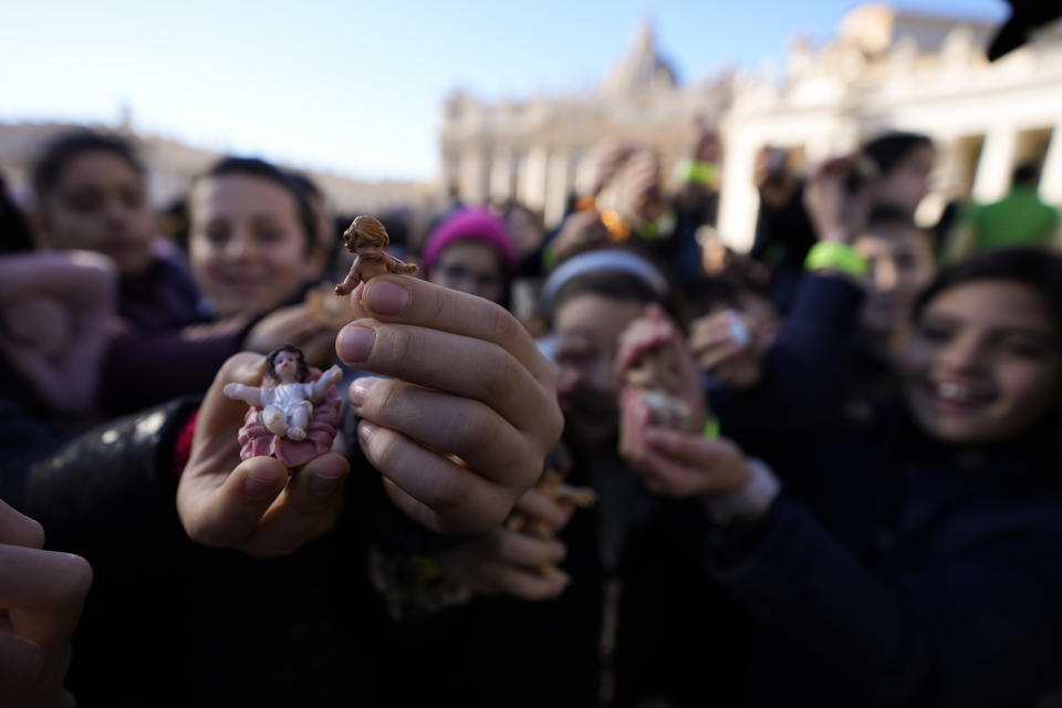 Children hold up statues of baby Jesus as they wait for Pope Francis' Angelus noon prayer he celebrates from the window of his studio overlooking St.Peter's Square, at the Vatican, Sunday, Dec. 17, 2023. (AP Photo/Alessandra Tarantino)