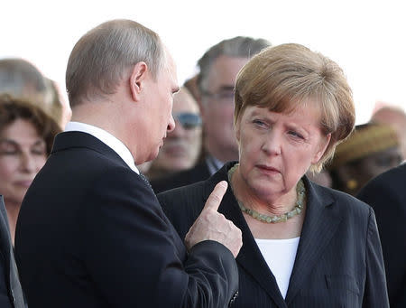 Russian President Vladimir Putin talks with German Chancellor Angela Merkel as they attend the International 70th D-Day Commemoration Ceremony in Ouistreham in this June 6, 2014 file photo. REUTERS/Kevin Lamarque/Files