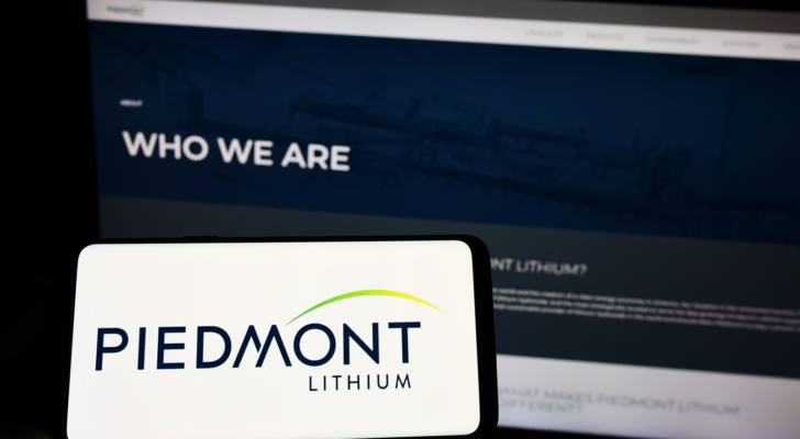 Person holding cellphone with logo of US mining company Piedmont Lithium Inc. (PLL) on screen in front of business webpage. Focus on phone display. Unmodified photo.