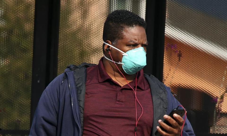 A man wears a mask while waiting for public transit in Alameda, California