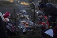 Gonzalo Rauque, 3, helps his mother, Constanza, rotate a rack of lamb during the multiday celebration of We Tripantu, the Mapuche new year, in the Corayen community of Los Rios, southern Chile, on Tuesday, June 21, 2022. (AP Photo/Rodrigo Abd)