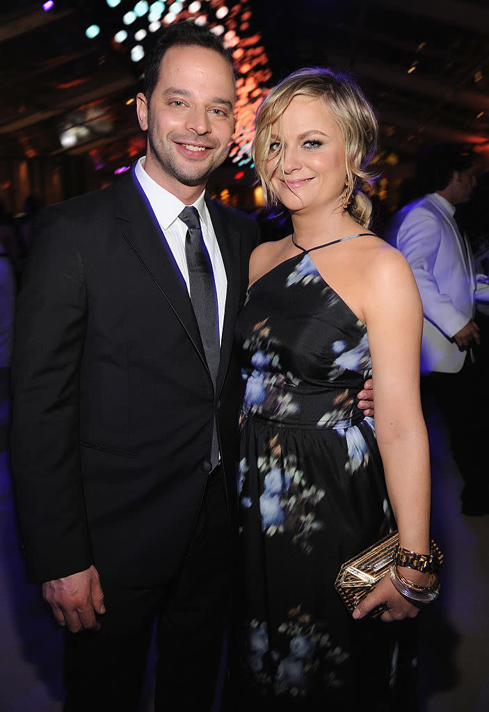 Nick in a black suit and tie, Amy in a floral dress with a halter neckline, holding a clutch