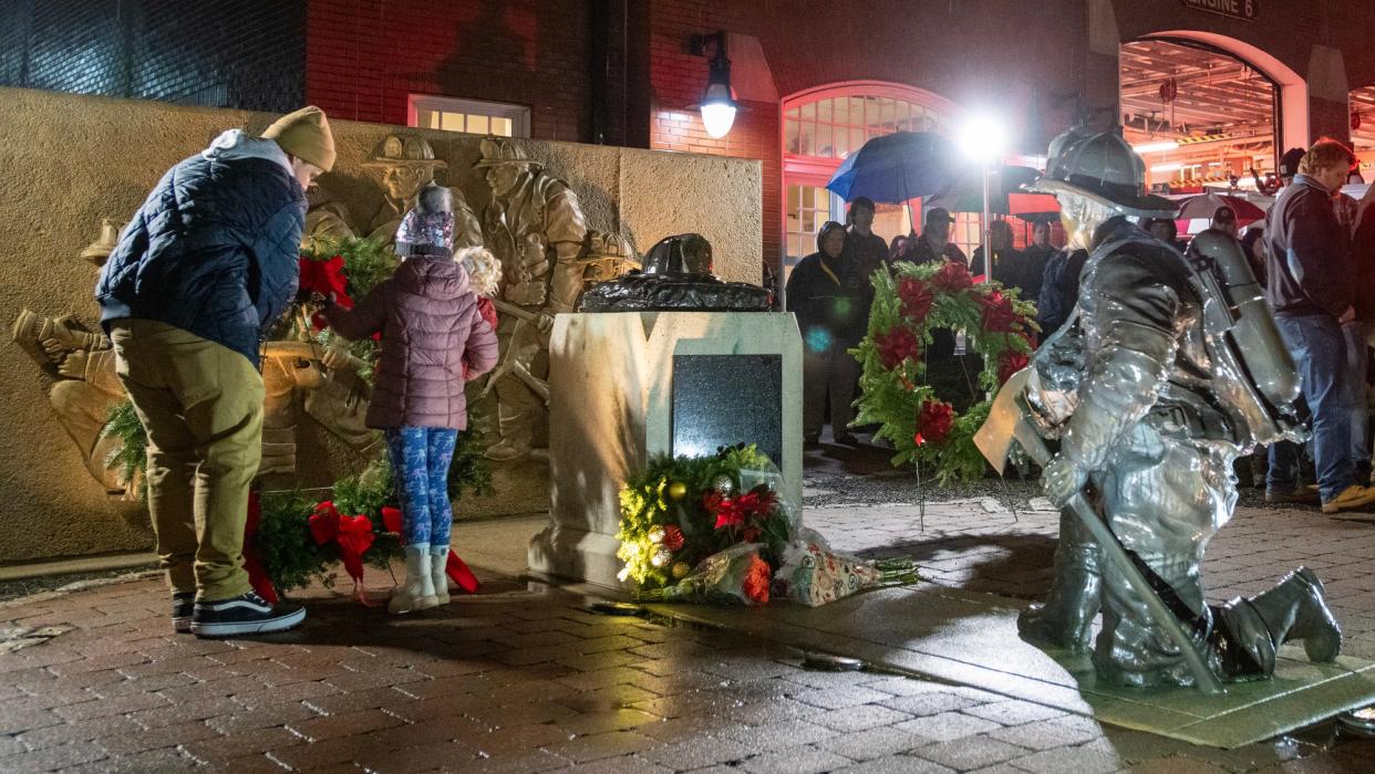 Firefighter Danny Spencer and his 7-year-old daughter, Maisy, place a wreath at the memorial in front of the Franklin Street Fire Station during a ceremony Sunday evening. Spencer’s father, Lt. Thomas E. Spencer, was one of six firefighters who died in the 1999 Cold Storage and Warehouse fire.