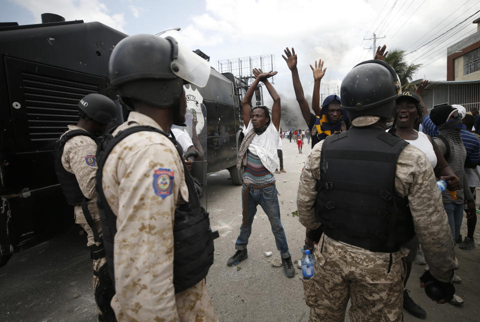 Protestors calling for the resignation of President Jovenel Moise raise their arms in front of a group of police in riot gear, in Port-au-Prince, Haiti, Friday, Oct. 4, 2019. After a two-day respite from the recent protests that have wracked Haiti's capital, opposition leaders urged citizens angry over corruption, gas shortages, and inflation to join them for a massive protest march to the local headquarters of the United Nations. (AP Photo/Rebecca Blackwell)