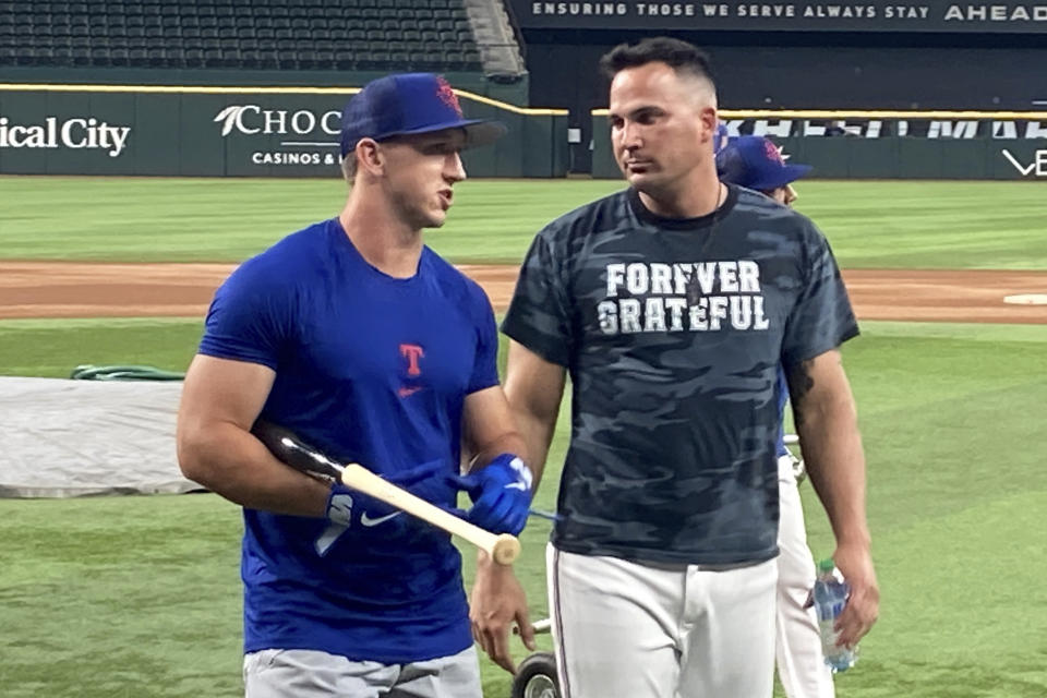 Texas Rangers first-round draft pick Wyatt Langford, left, talks with bench coach/offensive coordinator Donnie Ecker, right, after taking batting practice before a baseball game against the Tampa Bay Rays, Tuesday, July 18, 2023, in Arlington, Texas. (AP Photo/Stephen Hawkins)