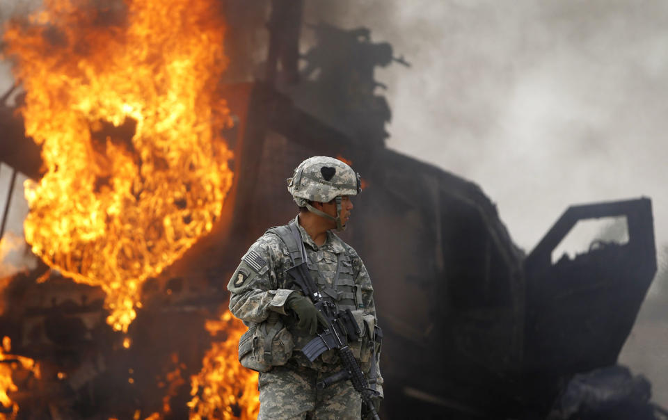 <p>Captain Melvin Cabebe with the US Army’s 1-320 Field Artillery Regiment, 101st Airborne Division stands near a burning M-ATV armored vehicle after it struck an improvised explosive device (IED) near Combat Outpost Nolen in the Arghandab Valley north of Kandahar, on July 23, 2010. (Photo: Bob Strong/Reuters) </p>