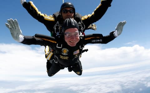 Former U.S. President George H.W. Bush (bottom) celebrates his 85th birthday by jumping with the Army's Golden Knight parachute team in a tandem jump in Kennebunkport - Credit: Reuters