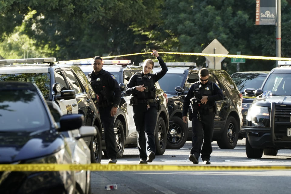 Sacramento Police officers cross under police tape at the scene of a fatal shooting that injured several others outside of a downtown Sacramento, Calif., night club in the early morning hours on Monday, July 4, 2022. (AP Photo/Rich Pedroncelli)