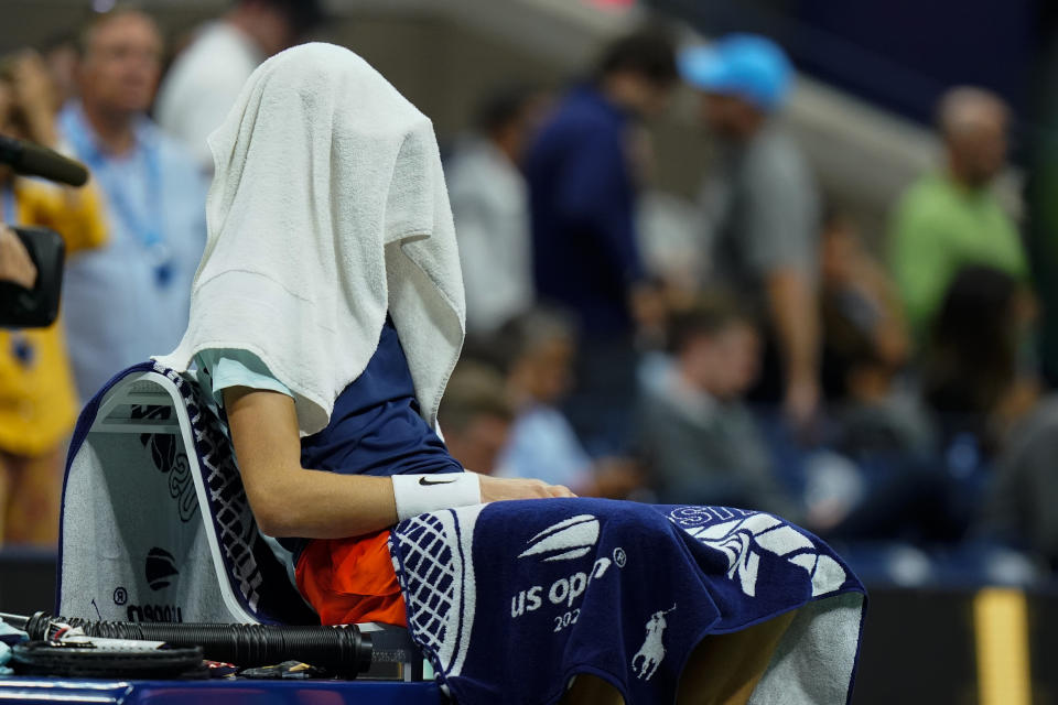 Jannik Sinner, of Italy, sits with a towel over his head between games as he plays Carlos Alcaraz, of Spain, during the quarterfinals of the U.S. Open tennis championships, Wednesday, Sept. 7, 2022, in New York. (AP Photo/Frank Franklin II)