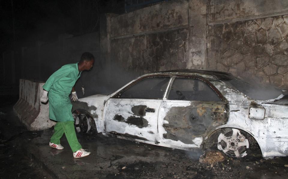 A firefighter looks at a destroyed car at the scene of an explosion outside the Jazira hotel in Mogadishu, January 1, 2014. Three bombs exploded within an hour outside the hotel in a heavily fortified district of the Somali capital on Wednesday, killing at least 11 people. (REUTERS/Feisal Omar)