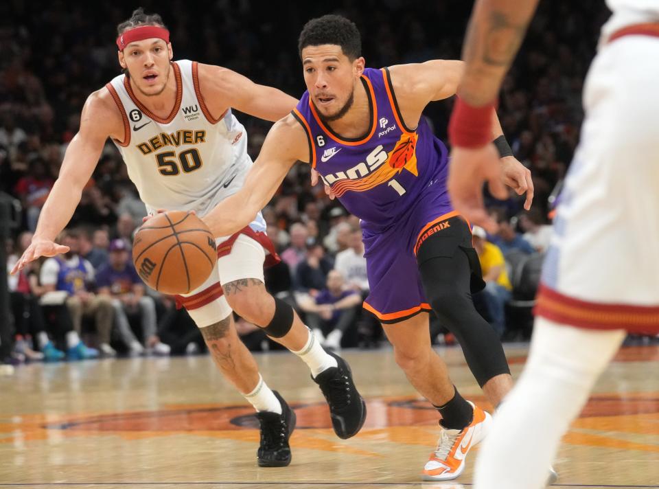 Phoenix Suns guard Devin Booker (1) drives past Denver Nuggets forward Aaron Gordon (50) in a game at Footprint Center in Phoenix on March 31, 2023.