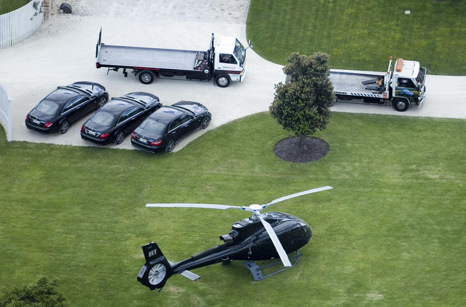 FILE- In this Jan. 20, 2012 file photo, tow trucks wait to remove vehicles from Kim Dotcom's house in Coatesville, north west of Auckland, New Zealand. On his way up, he fooled them all: journalists, judges, investors and companies. Then the man who renamed himself Kim Dotcom finally did it. With an eye for get-rich schemes and an ego gone wild, he parlayed his modest computing skills into a mega-empire, becoming the fabulously wealthy computer maverick he had long claimed to be. (AP Photo/NZ Herald, Natalie Slade, File) NEW ZEALAND OUT, AUSTRALIA OUT