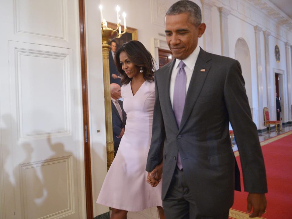 Barack and Michelle Obama walk together in the White House.
