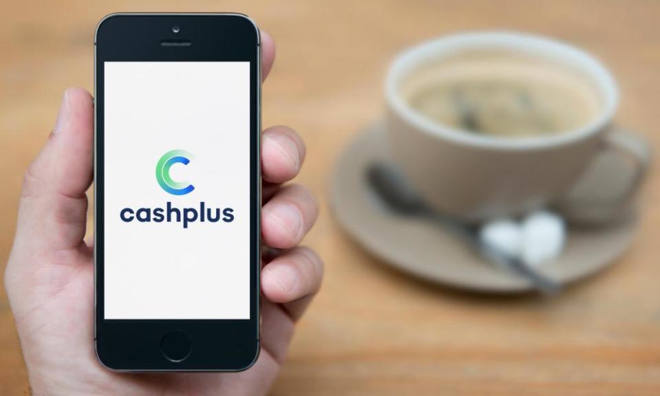 A man looks at his iPhone, which displays the Cash Plus logo