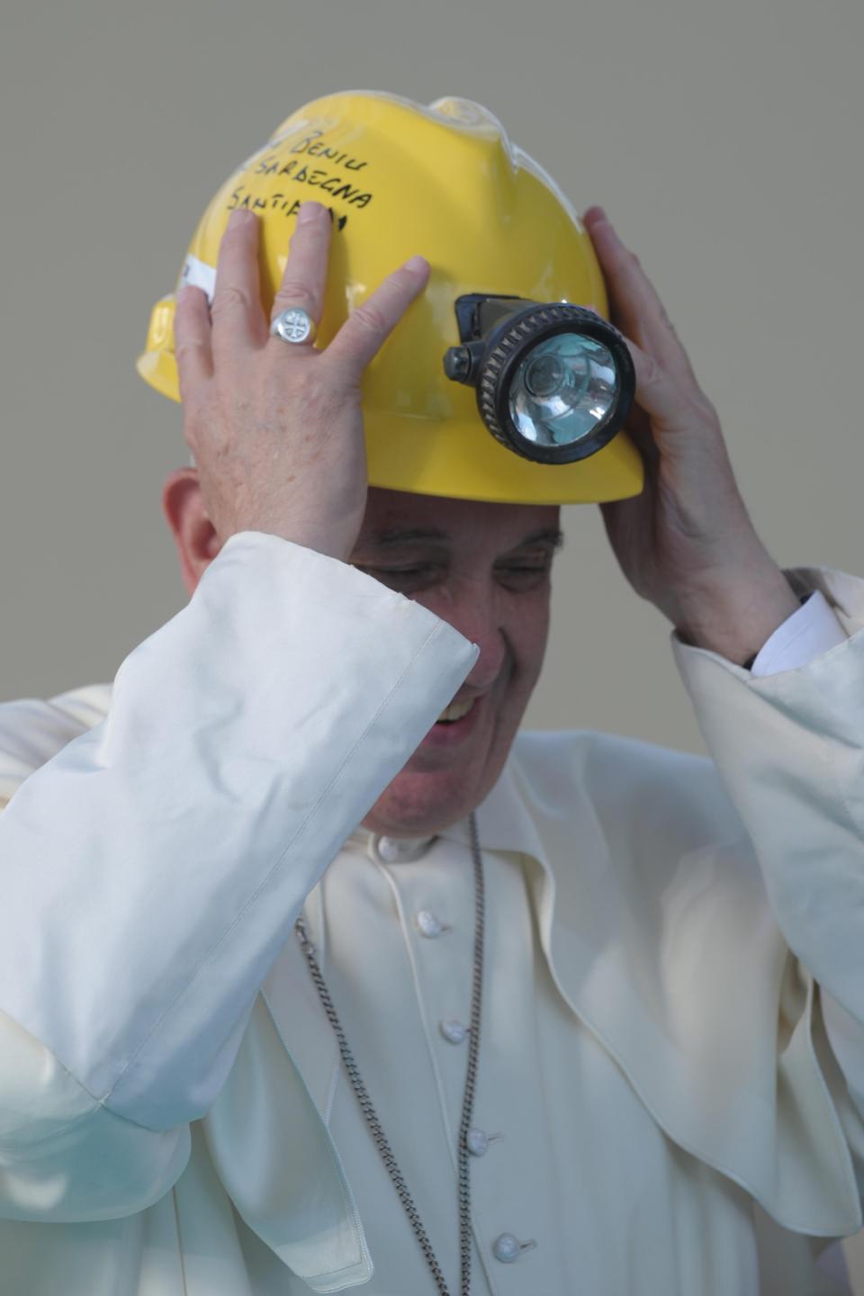 Pope Francis wears a hard hat he received from a miner during a mass outside the Shrine of Our Lady of Bonaria in Cagliari