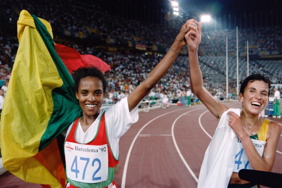 Ethiopia's Derartu Tulu (L) and Elana Meyer of South Africa join hands in a victory lap after the women's 10,000m final at the athletics event during the Barcelona 1992 Olympic Games on August 7, 1992 in Barcelona.  Tulu won the Olympic gold medal and Meyer took the silver. / AFP PHOTO / Pascal PAVANI        (Photo credit should read PASCAL PAVANI/AFP via Getty Images)