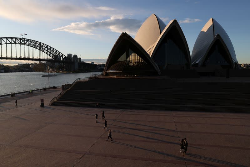 People are seen walking in front of the Sydney Opera House and Sydney Harbour Bridge in Sydney