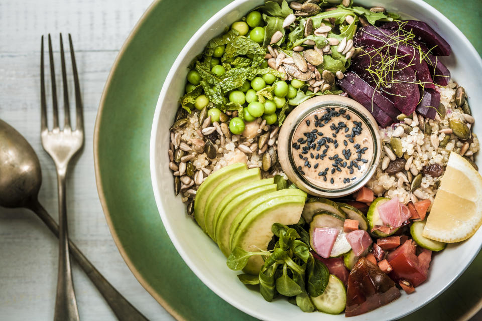 A healthy vegan/vegetarian lunch bowl of salads, grains, seeds, vegetables, avocado slices and a rich peanut-miso sauce.