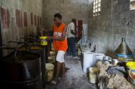 In this May 27, 2019 photo, Alsonce Jeune 32, extracts vetiver oil, used in fine perfumes, in Les Cayes, Haiti. Before the oil can be bought by top perfumers, the roots of the vetiver plant must also be distilled to their essence in a process that takes more than 24 hours. (AP Photo/Dieu Nalio Chery)