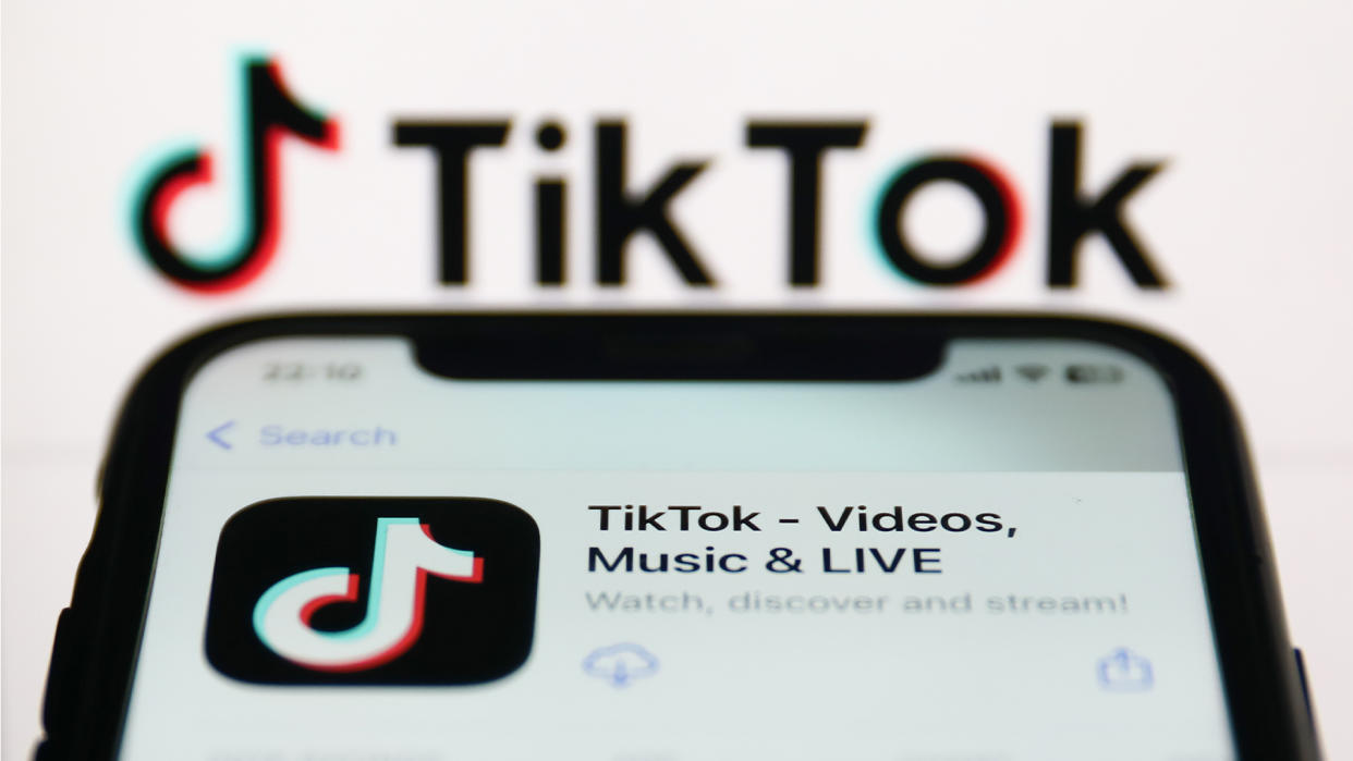  TikTok app on a phone with the TikTok logo in the background. 