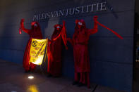 Demonstrators hold a banner reading "standing by and watching is no longer an option" outside the court building prior to the start of the court case of Milieudefensie, the Dutch arm of the Friends of the Earth environmental organization, against Shell in The Hague, Netherlands, Tuesday, Dec. 1, 2020. A landmark legal battle opened as climate change activists in the Netherlands go to court seeking an order for energy giant Shell to rein in its carbon emissions. (AP Photo/Peter Dejong)