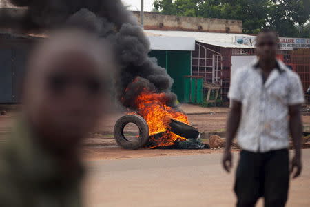 Men walk in front of a burning barricade set up by anti-coup protesters in Ouagadougou, Burkina Faso, September 21, 2015. REUTERS/Joe Penney