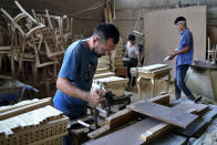 In this July 26, 2018, photo, Afghan musician Hakim Ebrahimi, left, a member of the Arikayn rock band, works at a furniture workshop on the outskirts of Tehran, Iran. The four rockers that make up the band, known as Arikayn, that plays Metallica-inspired ballads are Afghan refugees, and their struggles mirror those of millions of other Afghans who have fled to Iran during decades of war. (AP Photo/Ebrahim Noroozi)