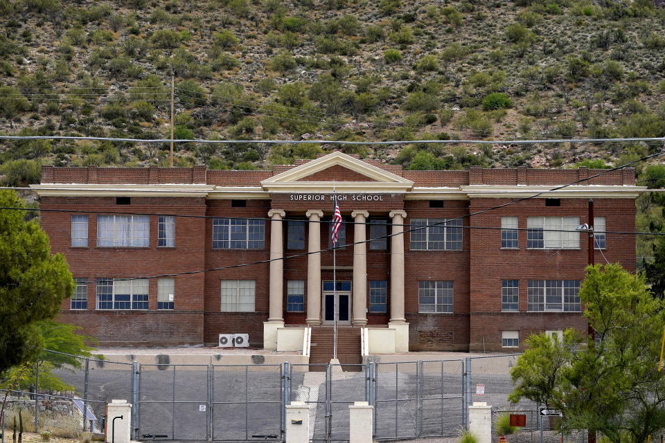 Fences surround the vacant Superior High School, Friday, June 9, 2023, in Superior, Ariz. The historic mining town in central Arizona is the subject of a tug of war between locals who want a copper mine developed nearby for economic benefit and Native American groups who say the land needed for mining is sacred and should be protected. (AP Photo/Matt York)