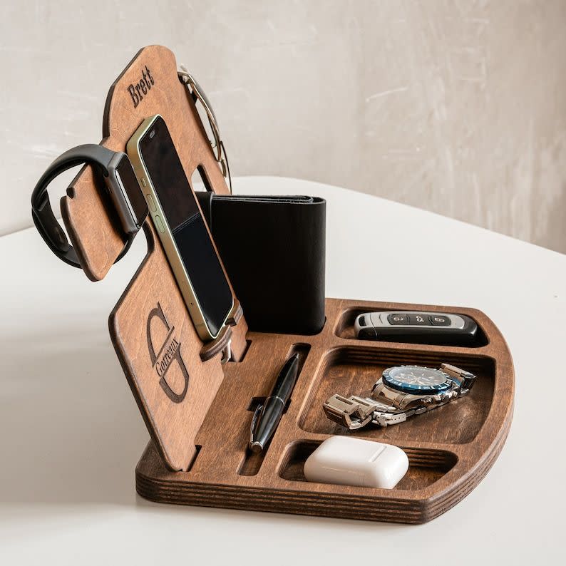 <p><strong>SkyWoodStudio</strong></p><p>etsy.com</p><p><strong>$58.24</strong></p><p>It's a charging station and catchall tray all in one. He can use the built-in organizers to store his everyday accessories, while also weaving chargers through the back to give his smartphone, headphones and smartwatch a boost.</p>