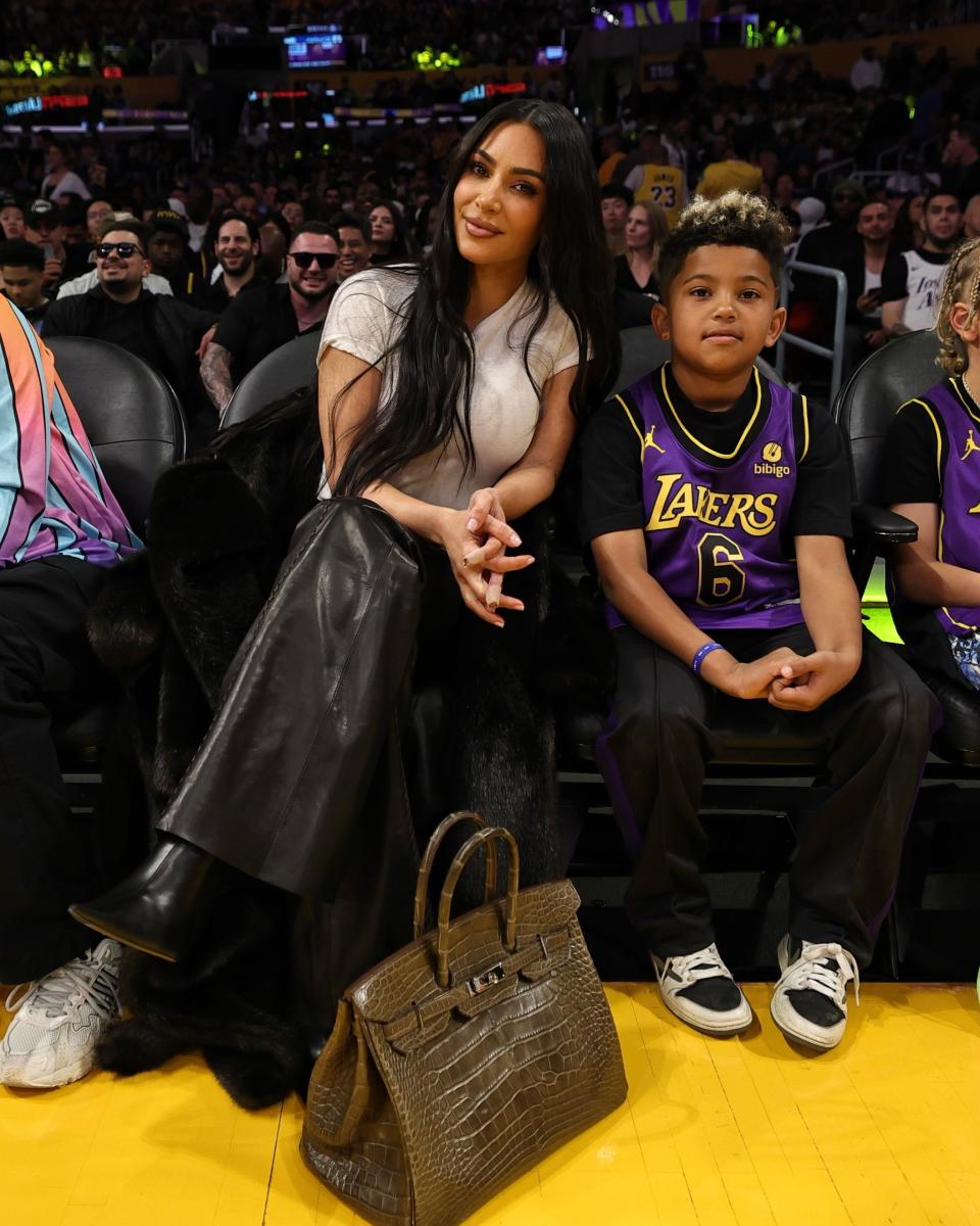 Kim Kardashian, her son Saint, and her Birkin bag at a Lakers game in March.