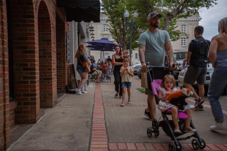 Brandon Waible strolls through downtown Columbia, Tenn., with his daughter Harbor Grace followed by his wife Andrea, carrying their daughter Harlow and joined by Halina during a First Fridays event on Friday, Aug. 8, 2021.