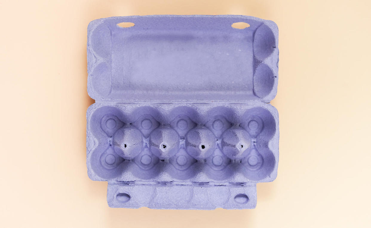 Purple egg carton without eggs on pastel background. (Getty Images)