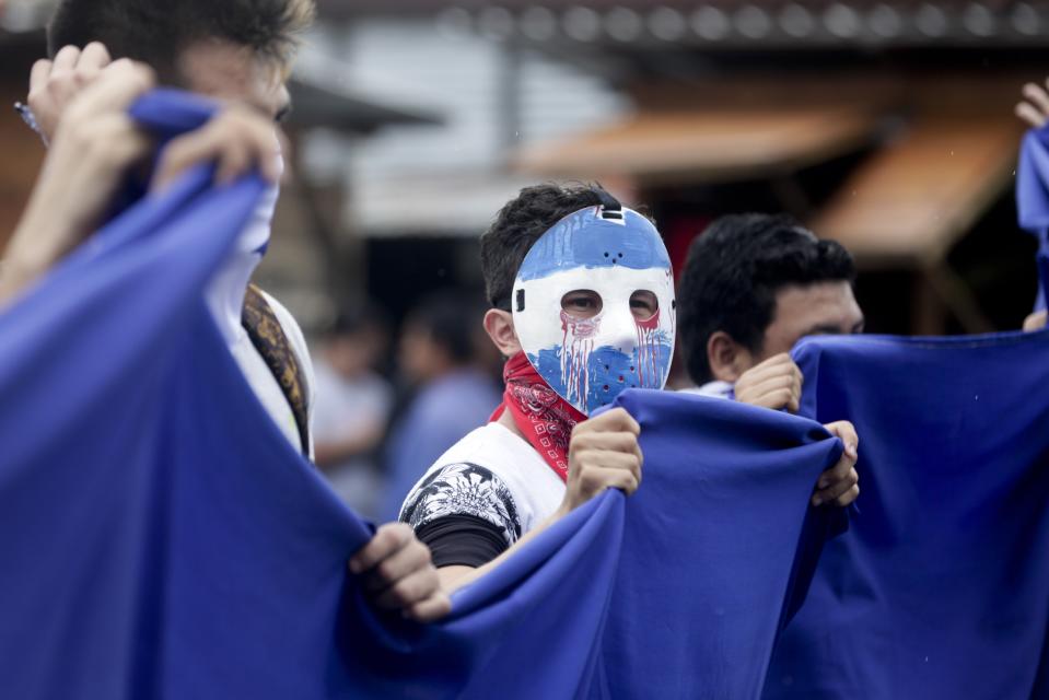 A masked demonstrator attends a protest outside the Jesuit run Universidad Centroamericana, UCA, demanding the university's allocation of its share of 6% of the national budget, in Managua, Nicaragua, Thursday, Aug. 2, 2018. Universities in Nicaragua are closed since mid-April as students are demanding the resignation of President Daniel Ortega and the release of all political prisoners. (AP Photo/Arnulfo Franco)