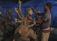 An artisan prepare a clay idol of Hindu Goddess Durga ahead of the Hindu religious festival season in Hyderabad, India, Wednesday, Oct. 7, 2020. The health ministry on Tuesday issued guidelines for large gatherings during the upcoming religious festival season and barred people from touching idols and holy books in such events to prevent the spread of infection. Health experts have warned the gatherings during the upcoming festivals have the potential for the virus to spread. (AP Photo/Mahesh Kumar A.)