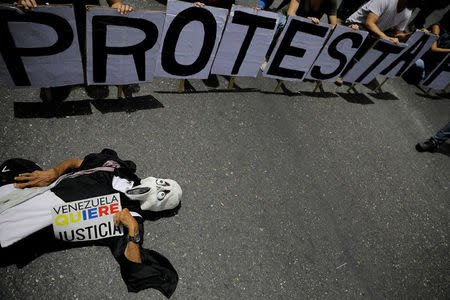 A demonstrator holds a banner that reads "VENEZUELA WANTS JUSTICE" during a rally called by health care workers and opposition activists against Venezuela's President Nicolas Maduro in Caracas, Venezuela May 22, 2017. The banner on the top reads "Protest". REUTERS/Carlos Barria