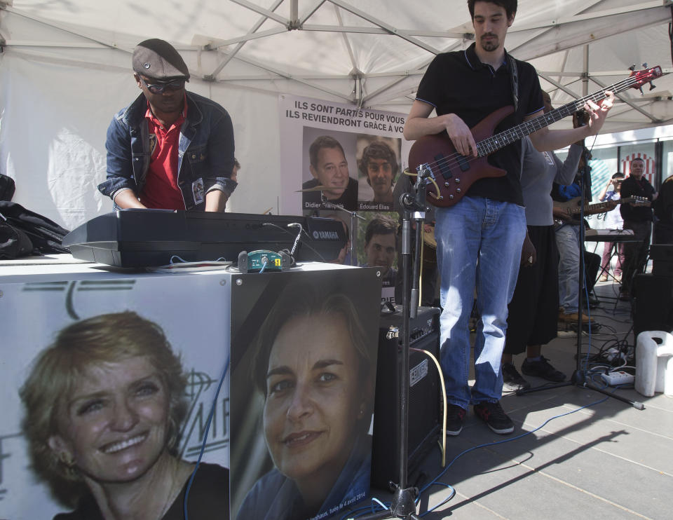 The pictures of Associated Press correspondent Kathy Gannon, who was wounded, left, and photographer Anja Niedringhaus, 48, who was killed April 4, 2014 in Afghanistan are displayed next to a playing reggae band in Paris, Saturday, April 5, 2014. Support group of the four French journalists taken hostages in Syria, Edouard Elias, Pierre Torres, Nicolas Henin and Didier Francois organized a commemoration for the late Anja Niedringhaus and AP correspondent Kathy Gannon, who was wounded in Afghanistan. (AP Photo/Michel Euler)