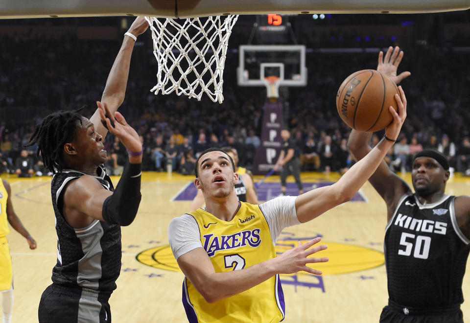 Lonzo Ball (C) goes to the hole against Kings guard De’Aaron Fox (L) on Tuesday night. (AP)